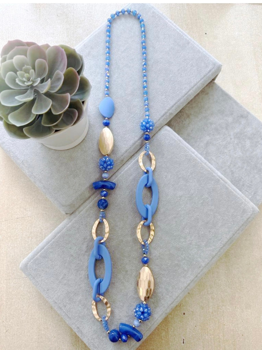 Add interest to your look with this stunning blue and gold long necklace. It features a combination of textures and unique shapes, making it a perfect statement piece for any outfit. Elevate your style and stand out from the crowd with this eye catching necklace.