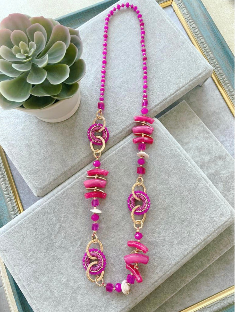 Add interest to your look with this stunning pink and gold long necklace. It features a combination of textures and unique shapes, making it a perfect statement piece for any outfit. Elevate your style and stand out from the crowd with this eye catching necklace.