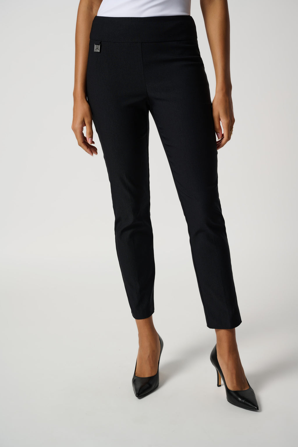 These black Joseph Ribkoff slim-fit pull-on trouser, constructed in a woven Millennium fabric, provide just the right amount of weight and stretch for a form-flattering fit. Also feature a structured contour waistband and a subtle JR tab ornament on the front so you can feel comfortable and confident wherever the day takes you.